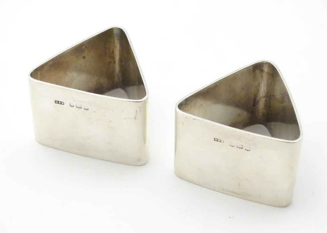 A pair of Art Deco silver napkin rings of triangular: A pair of Art Deco silver napkin rings of triangular form. Hallmarked Birmingham 1921 maker Docker & Burn Ltd. (98g)