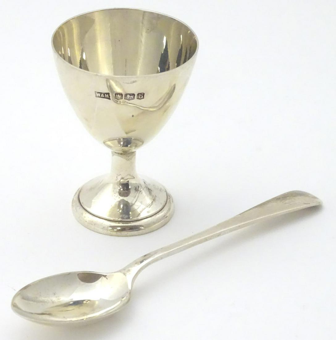 A silver pedestal egg cup together with a spoon. Both: A silver pedestal egg cup together with a spoon. Both hallmarked Sheffield 1919 maker Walker & Hall (2)