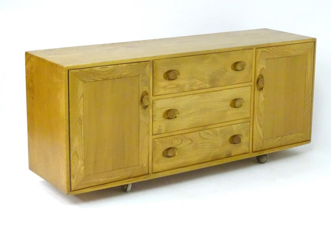 Vintage Retro : a British Ercol blonde Elm Windsor: Vintage Retro : a British Ercol blonde Elm Windsor sideboard (no.455) launched in 1961 with gold label, having three drawers flanked by cupboard doors, 61'' wide
