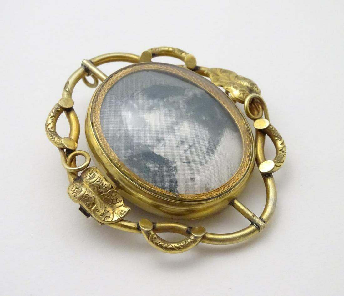 A 19thC locket brooch, the scrolling foliate surround: A 19thC locket brooch, the scrolling foliate surround with central revolving locket section. 2 ¼'' high overall.