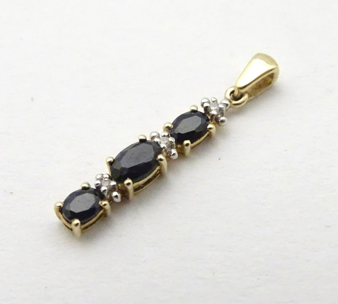 A 9ct gold pendant set with spinels and diamonds, 1'': A 9ct gold pendant set with spinels and diamonds, 1'' long.