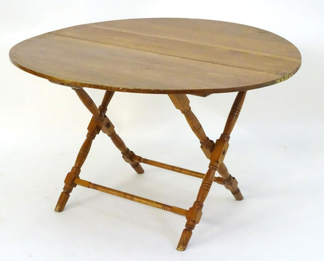 A late 19thC pine topped coaching table with a folding: A late 19thC pine topped coaching table with a folding base and four turned legs united by turned stretchers. Bears ivorine label 'Thornton & Herne, 13 Little Cadogan Place, Pont Street S.W. Patent No