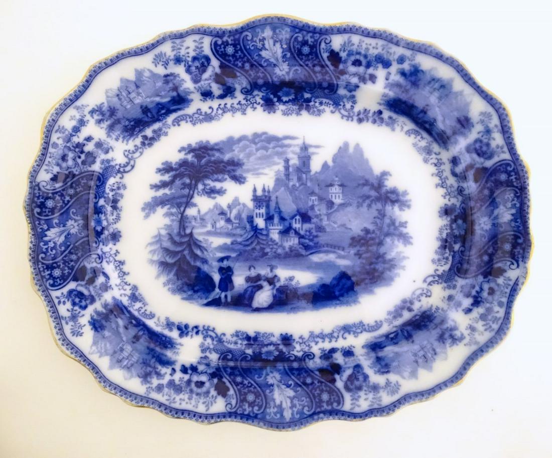 A Victorian blue and white meat plate in the pattern: A Victorian blue and white meat plate in the pattern Non Pareil, depicting figures in a landscape with a church, bridge etc. with a gilt rim, by Burgess and Leigh Middleport Pottery. Marked under. App