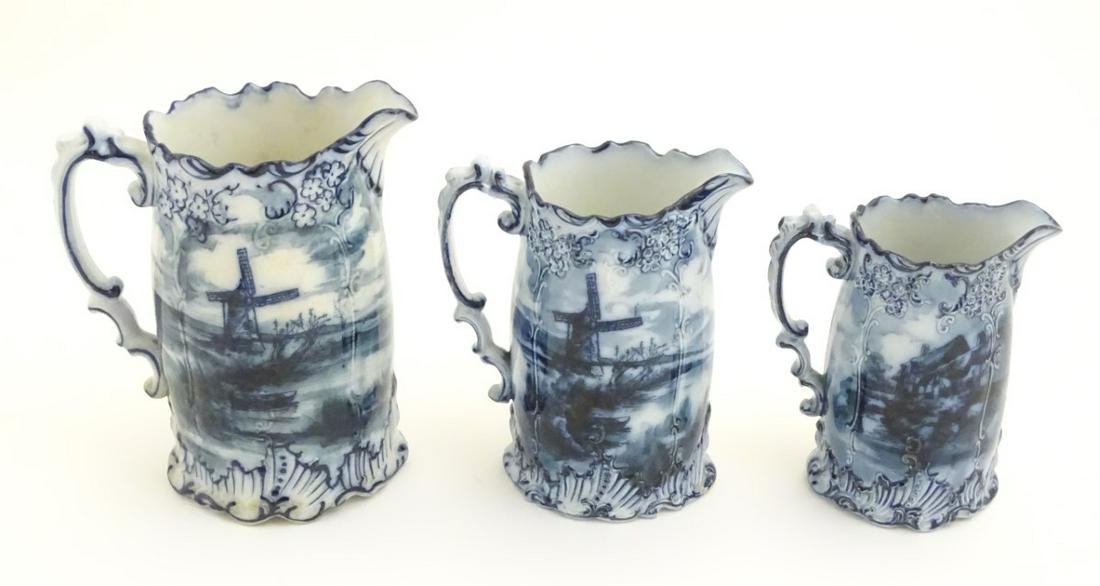 Three Victorian blue and white graduated jugs with: Three Victorian blue and white graduated jugs with transfer decoration depicting landscapes with buildings, castles, windmills etc. with relief decoration of natural forms flowers and shells. Marked R
