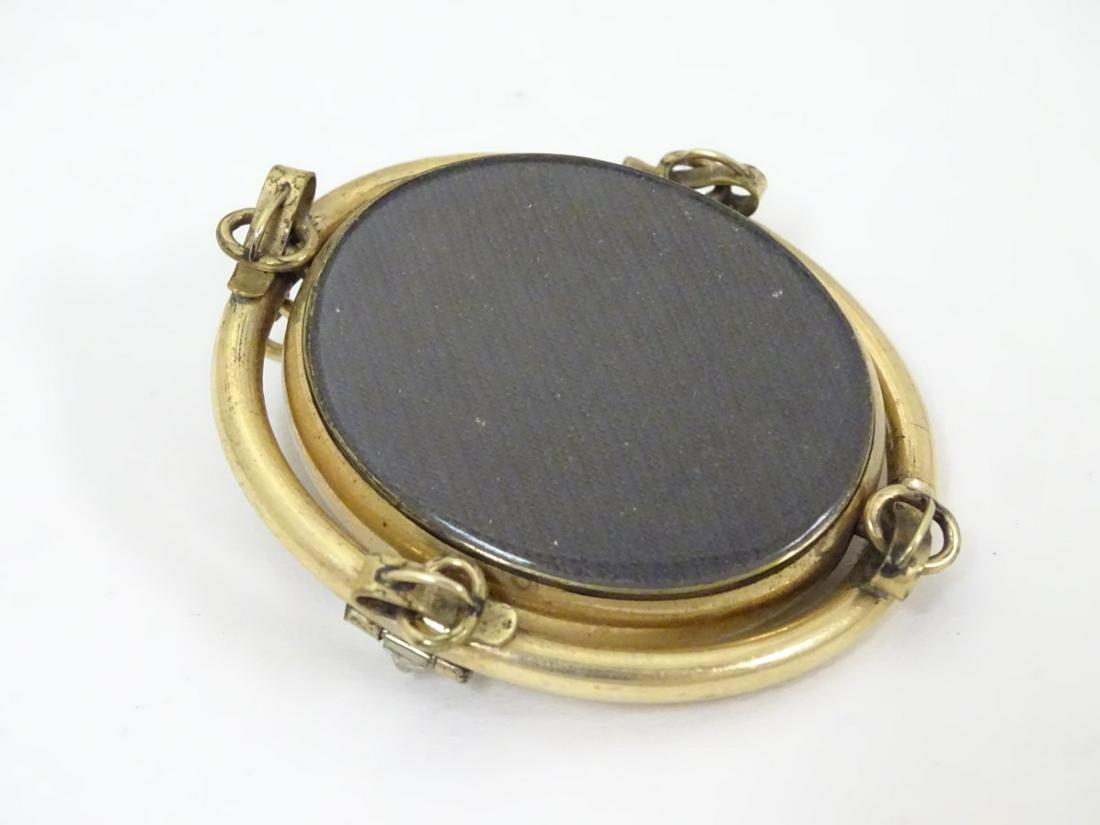 A Victorian gilt metal brooch with central oval: A Victorian gilt metal brooch with central oval rotating locket section 2'' high Category: JEWELLERY