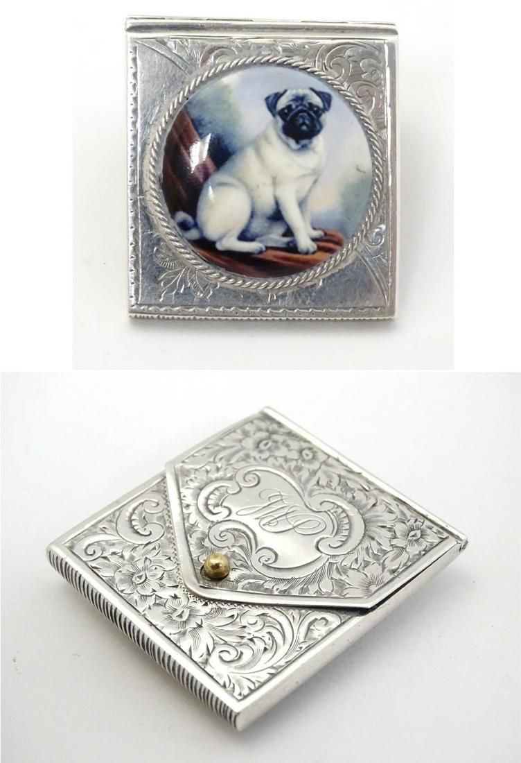 A white metal vesta case of envelope form, with striker: A white metal vesta case of envelope form, with striker under, and having later applied ceramic cabochon depicting a seating pug dog. Approx 1 3/4'' x 1 1/2'' x 1/4''