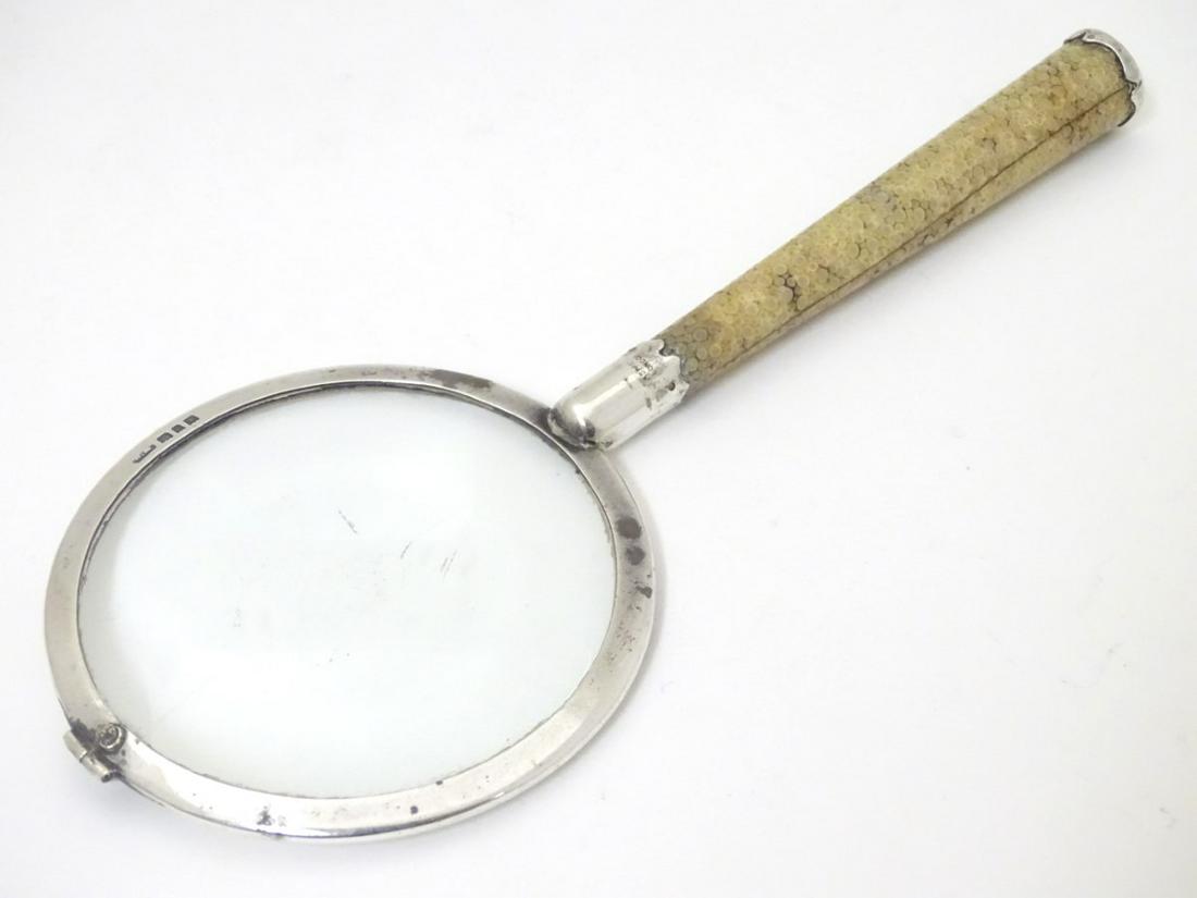 A silver magnifying glass with shagreen covered handle.: A silver magnifying glass with shagreen covered handle. Retailed by Asprey London and hallmarked London 1927 maker W.M 7 1/4'' long
