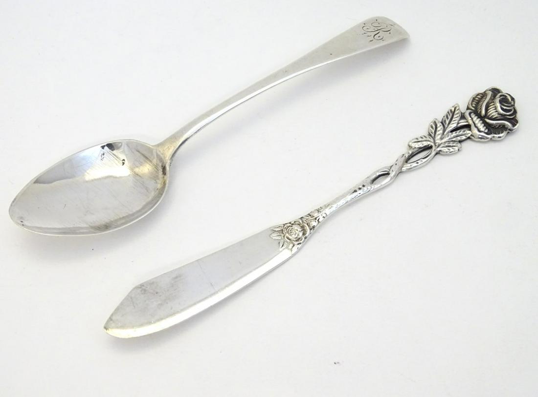 A .800 German silver butter knife with rose decoration: A .800 German silver butter knife with rose decoration to handle together with a teaspoon hallmarked London 1824. (2)