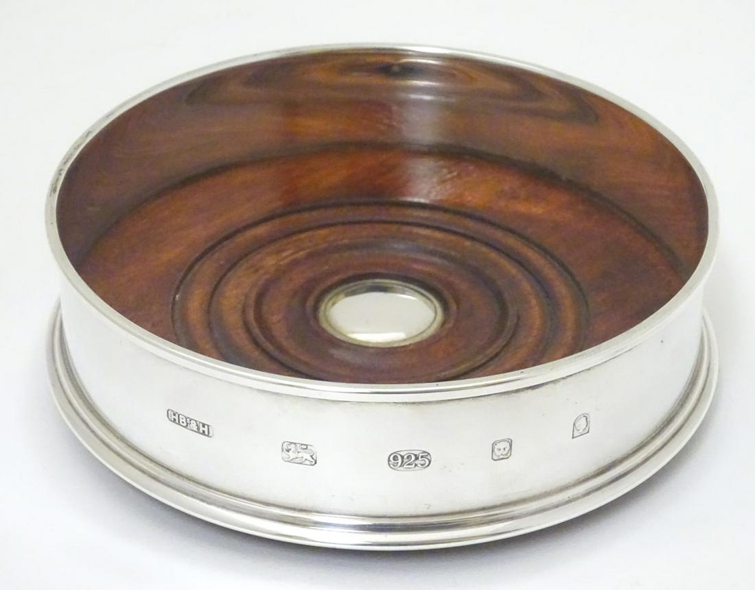 An Elizabeth II silver bottle coaster / decanter stand: An Elizabeth II silver bottle coaster / decanter stand with turned wooden base. Maker Harrison Brothers & Howson Ltd 5'' diameter