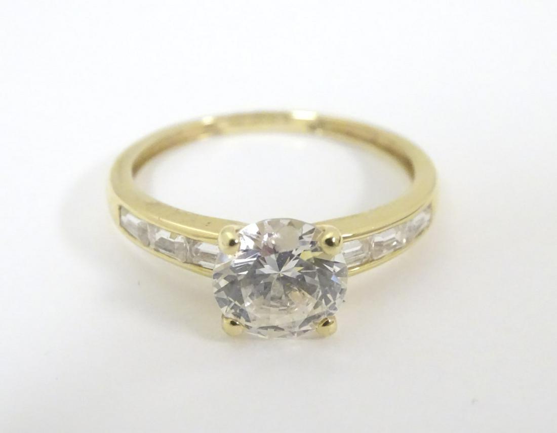 A 14 ct gold ring set with a large central cubic: A 14 ct gold ring set with a large central cubic zirconia flanked by 3 baguette cut cubic zirconia to shoulders. Ring size approx. Q 1/2