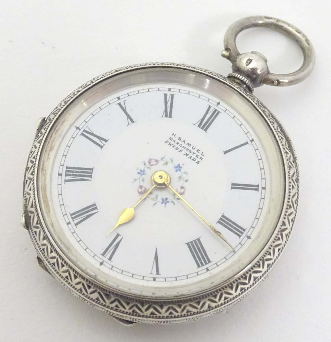 A silver cased topwind pocket watch by H. Samuel,: A silver cased topwind pocket watch by H. Samuel, Manchester (marked 'Swiss made'), the enamel dial decorated with a floral garland. The case engraved overall. 1 1/2'' in diameter
