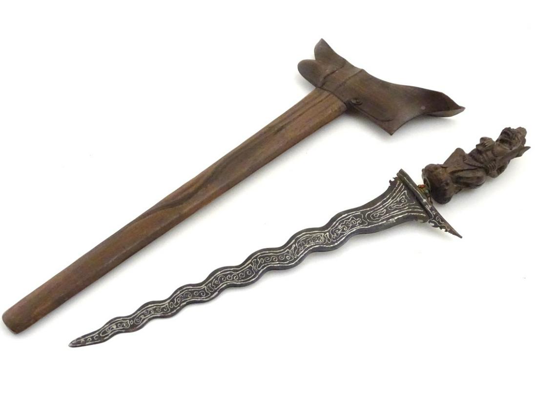 An Indonesian Kris dagger and wooden sheath, 15'',: An Indonesian Kris dagger and wooden sheath, 15'', Damascus blade of waved form, terminating in a carved wooden hilt formed as a mythical beast. 25'' overall