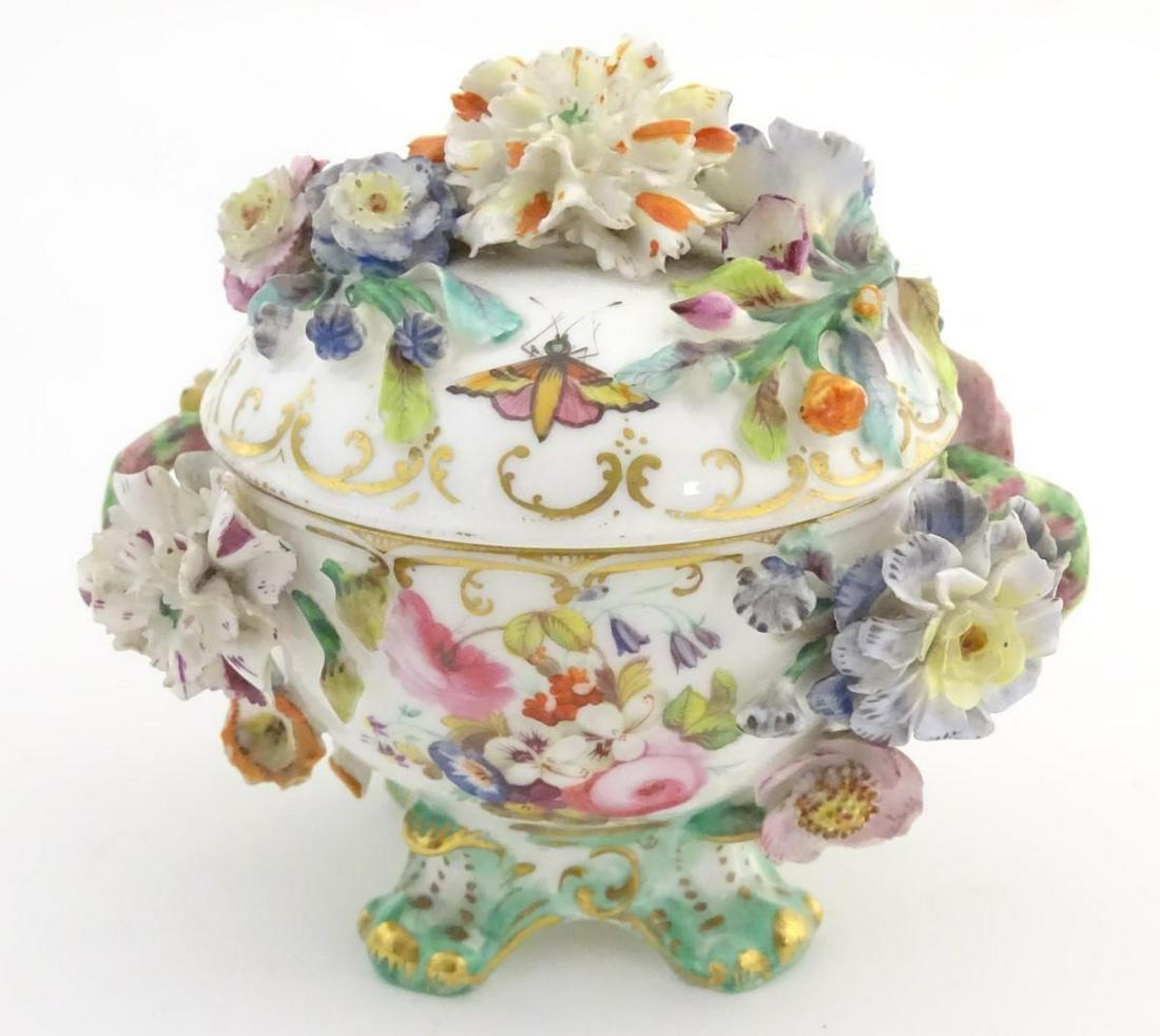 A twin handled German pot and cover on scrolled feet,: A twin handled German pot and cover on scrolled feet, decorated in relief with encrusted flowers, ladybirds, etc. with gilt highlights. Approx. 3 3/4" high.