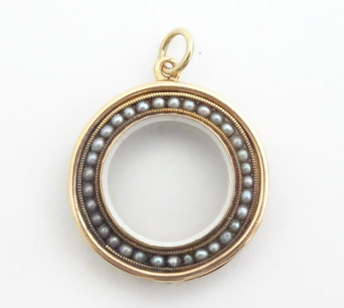 A Victorian 9ct gold and gilt metal locket of circular: A Victorian 9ct gold and gilt metal locket of circular form with central glazed locket section bordered by seed pearls. 3/4" diameter
