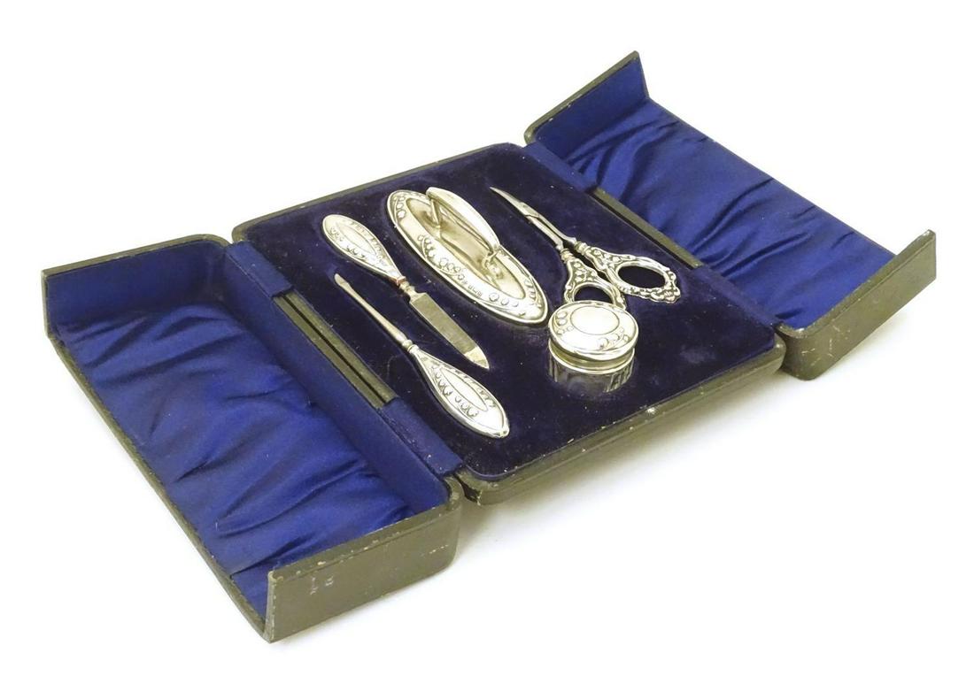 A cased manicure set comprising silver handled: A cased manicure set comprising silver handled scissors, buffer, file etc and a silver topped pot. Hallmarked Birmingham 1911/1912 maker Boots Pure Drug Co.