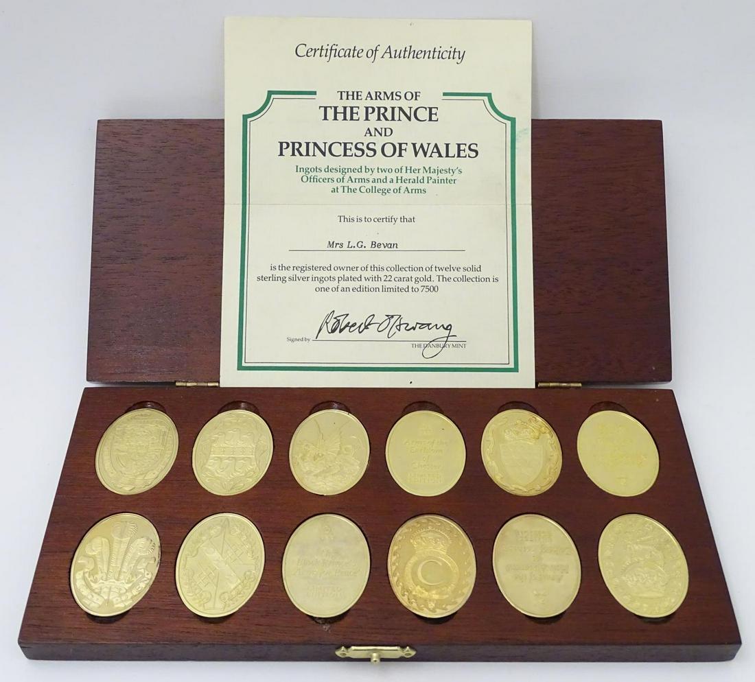 A cased collection of gold plated sterling silver oval: A cased collection of gold plated sterling silver oval ingots, Danbury Mint c1981, a limited edition of 7500, 'The Arms of the Prince and Princess of Wales', with authenticity certificate.
