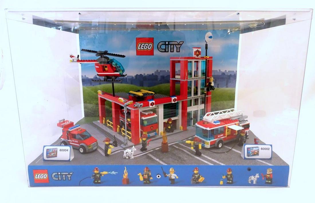 Toy: A Lego City shop display unit featuring a fire: Toy: A Lego City shop display unit featuring a fire station, model no. 60004 and a fire truck, model no. 60002. With provision for batteries for lights and motorised parts. Case approx. 15" high x 23