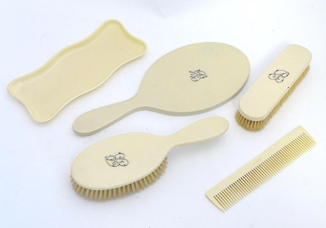 An early 20thC ivorine dressing table items to include,: An early 20thC ivorine dressing table items to include, hand mirror and two brushes etc. some with applied silver monograms for London 1904. Mirror approx. 12" overall. (5)