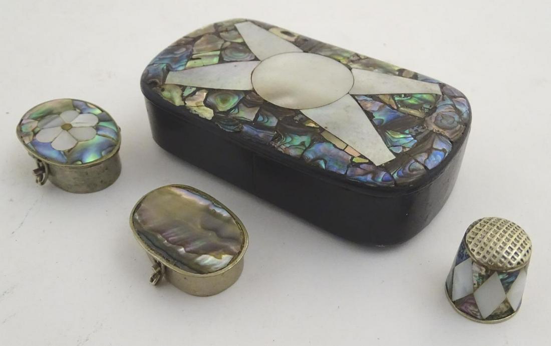 A papier mache snuff box, the hinged lid with mother of: A papier mache snuff box, the hinged lid with mother of pearl and abalone decoration. Together with two white metal pill boxes with inlaid abalone, one with mother of pearl flower detail, both marked 