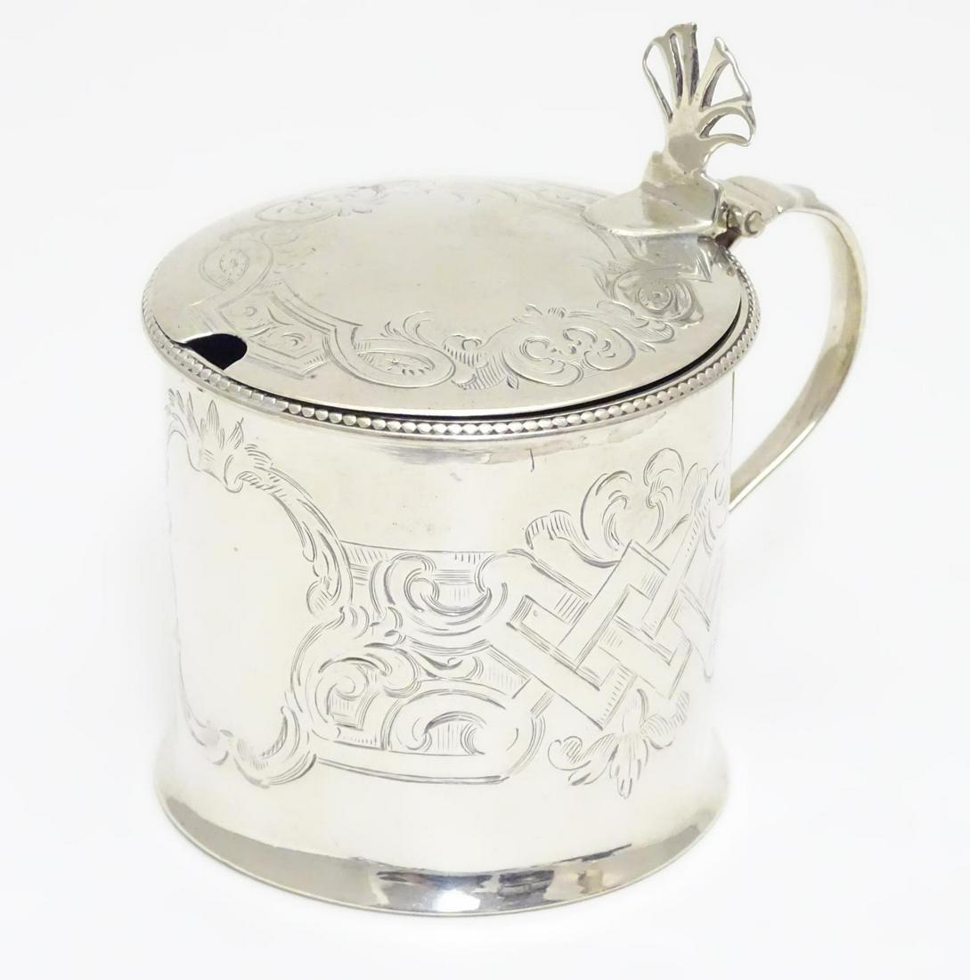 A sliver mustard pot with engraved decoration, hinged: A sliver mustard pot with engraved decoration, hinged lid and blue glass liner. Hallmarked London 1777 maker Thomas Daniell. Approx 3" high