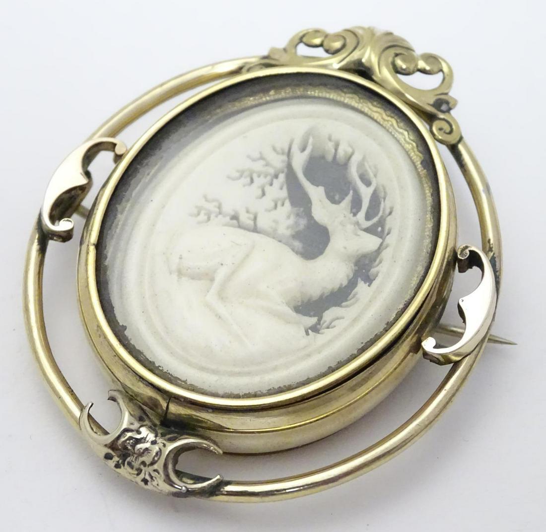 A Victorian mourning brooch / locket the central: A Victorian mourning brooch / locket the central section with carved stag detail to one side and mourning lock of hair to other. 2 1/2" high