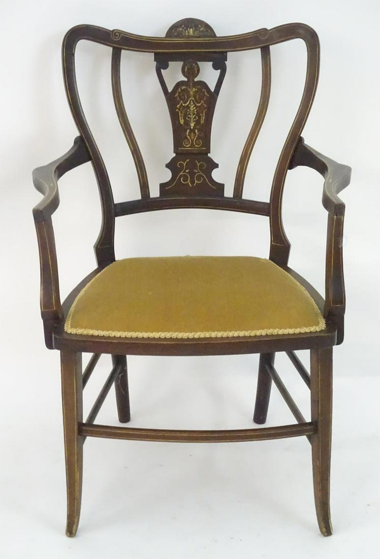 An Edwardian marquetry inlaid chair, with a shaped: An Edwardian marquetry inlaid chair, with a shaped backrest, swept arms and standing on tapering legs united by a box stretcher. 25" wide x 22" deep x 35" high.