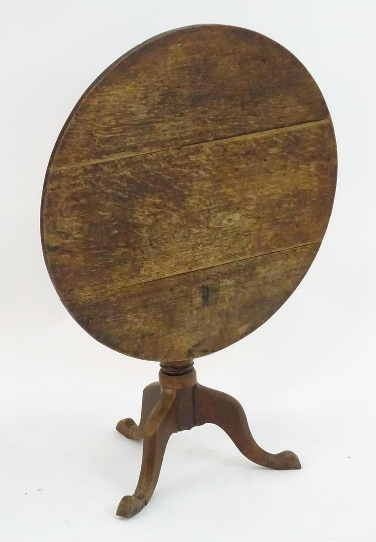 A late 18thC oak tripod table with a three plank top: A late 18thC oak tripod table with a three plank top above a turned pedestal and three cabriole legs terminating in pad feet. 34" in diameter x 29" high.