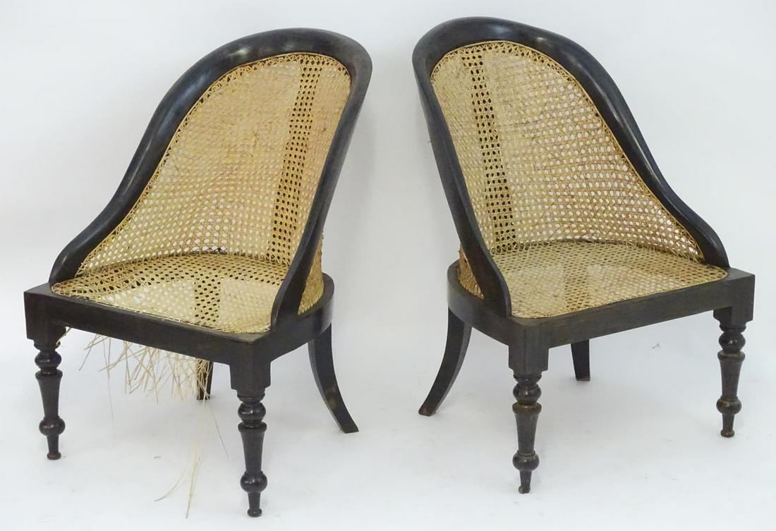 A pair of 19thC low bergere chairs with caned seats and: A pair of 19thC low bergere chairs with caned seats and backrest, the chairs raised on turned tapering front legs and sabre back legs. 22" wide x 27" deep x 32" high.