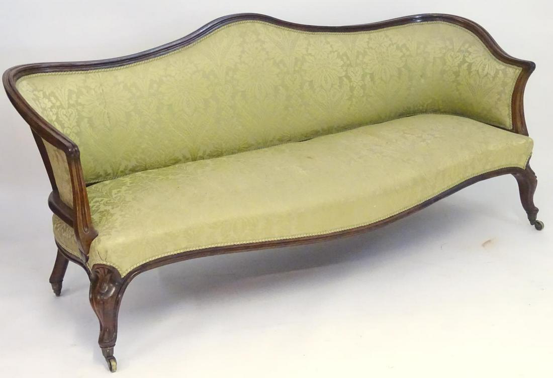 A large 19thC sofa with a walnut show wood frame and: A large 19thC sofa with a walnut show wood frame and camel back above an upholstered backrest and sprung seat, the sofa raised on carved cabriole legs terminating in brass castors. 79" long x 28" wide