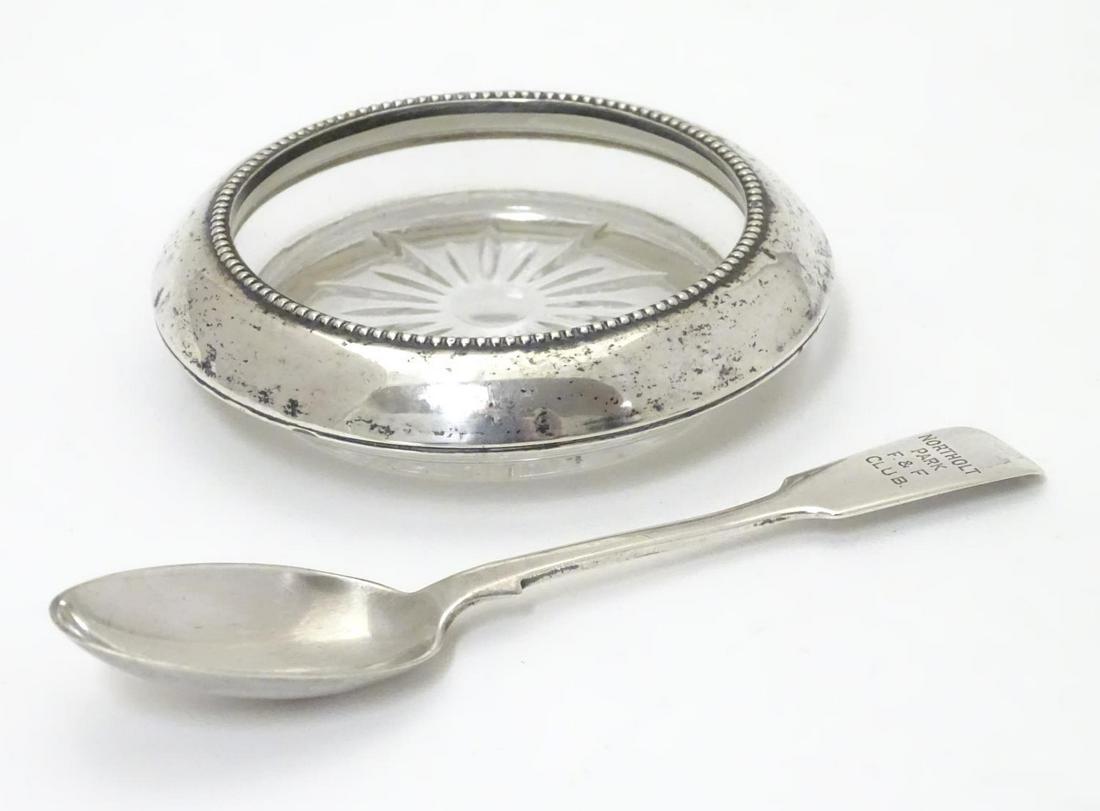 An American glass coaster with silver mount marked: An American glass coaster with silver mount marked Frank M Whiting & Co Sterling. 4" diameter .Together with a silver fiddle pattern teaspoon engraved Northolt Park F&F Club. Hallmarked London 1903 ma