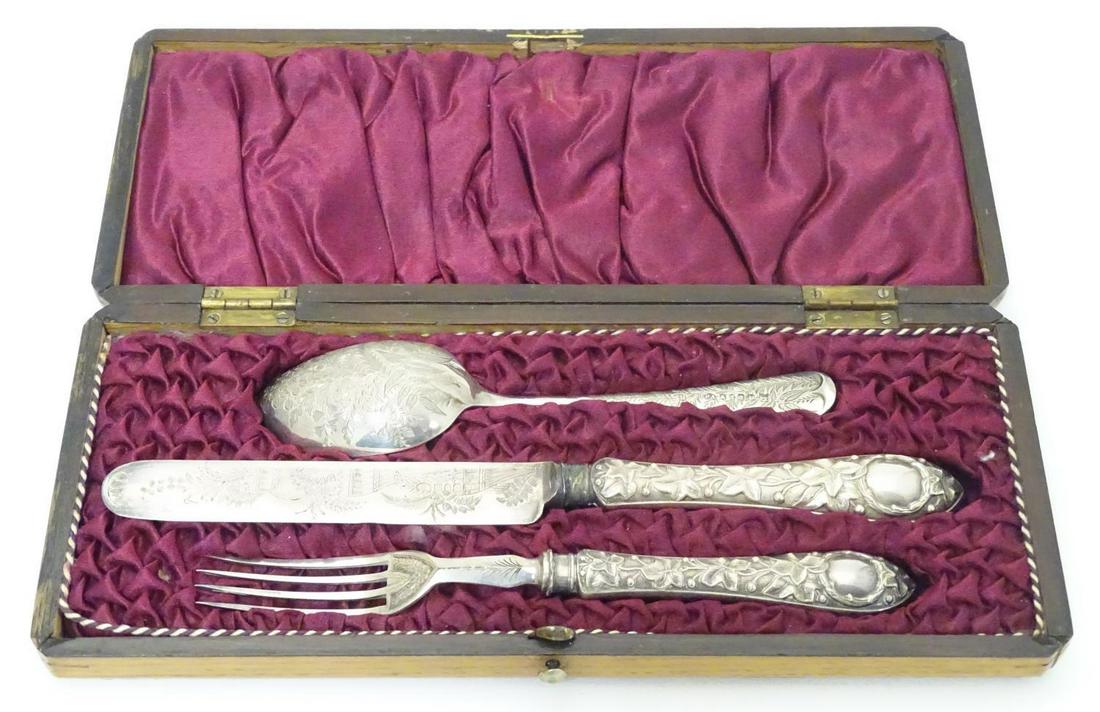 A knife and fork with foliate decoration to handles: A knife and fork with foliate decoration to handles together with a spoon with foliate detail. In a wooden case the case approx. 10" wide.