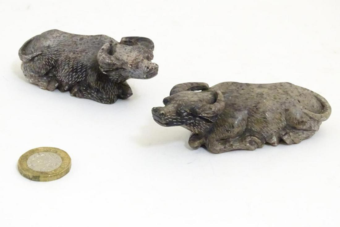 A pair of Oriental carved soapstone models of recumbent: A pair of Oriental carved soapstone models of recumbent water buffalo. Incised marks under. Approx. 1" high x 3 1/2" long