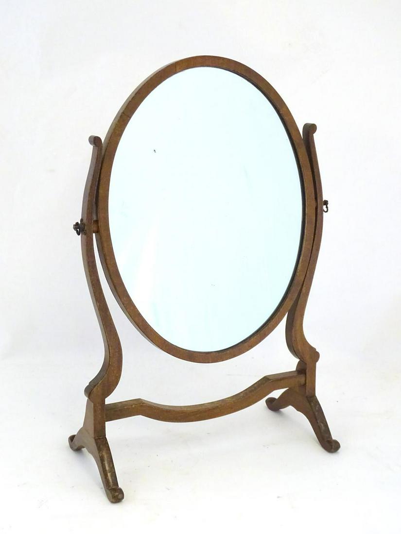 An early / mid 20thC mahogany dressing table mirror: An early / mid 20thC mahogany dressing table mirror with an oval surround and shaped frame. 16" wide x 24" high.
