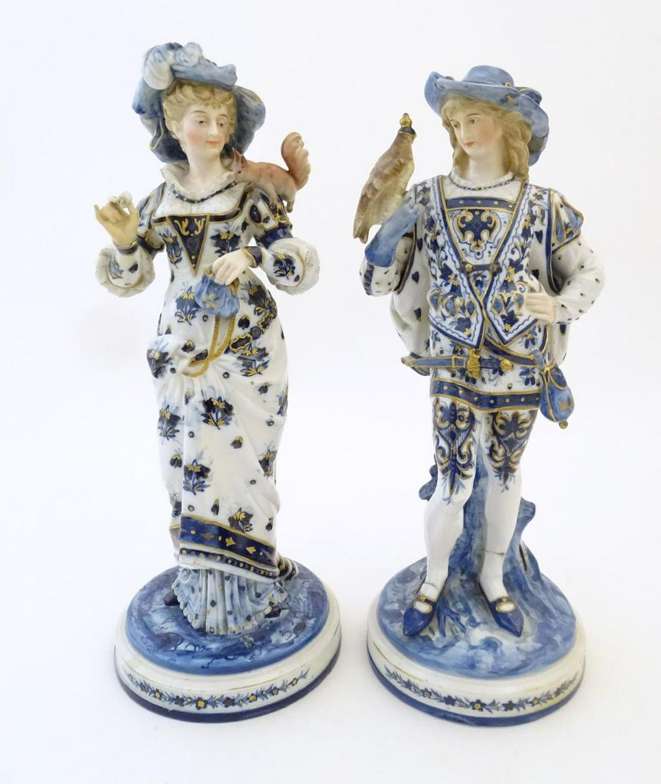 A pair of blue and white KPM figures with gilt: A pair of blue and white KPM figures with gilt highlights, comprising a female figure wearing a hat and holding a purse with a squirrel perched on her shoulder, and a gentleman wearing a gauntlet hold