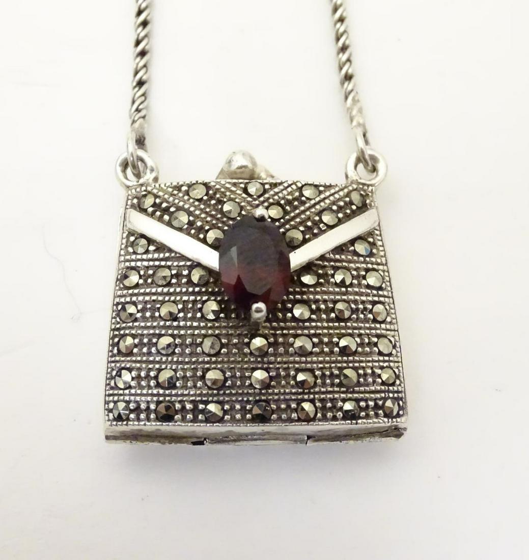 A silver pendant / vinaigrette formed as a purse /: A silver pendant / vinaigrette formed as a purse / handbag, set with marcasite and red stone detail. Approx. 25" long overall
