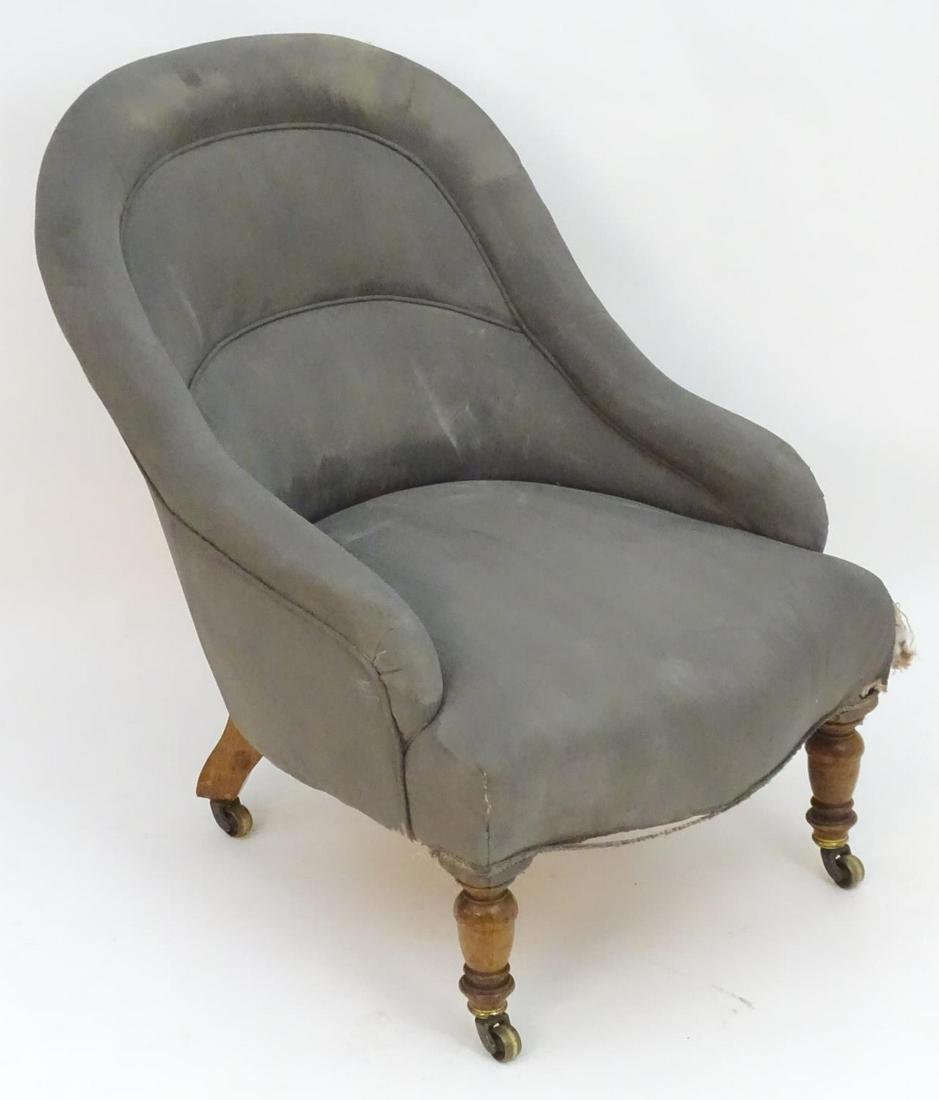 A small early 20thC upholstered tub armchair with: A small early 20thC upholstered tub armchair with walnut legs and brass castors. Stamped L.20264 to back leg. Re upholstery. Measuring 23" wide x 29" high.