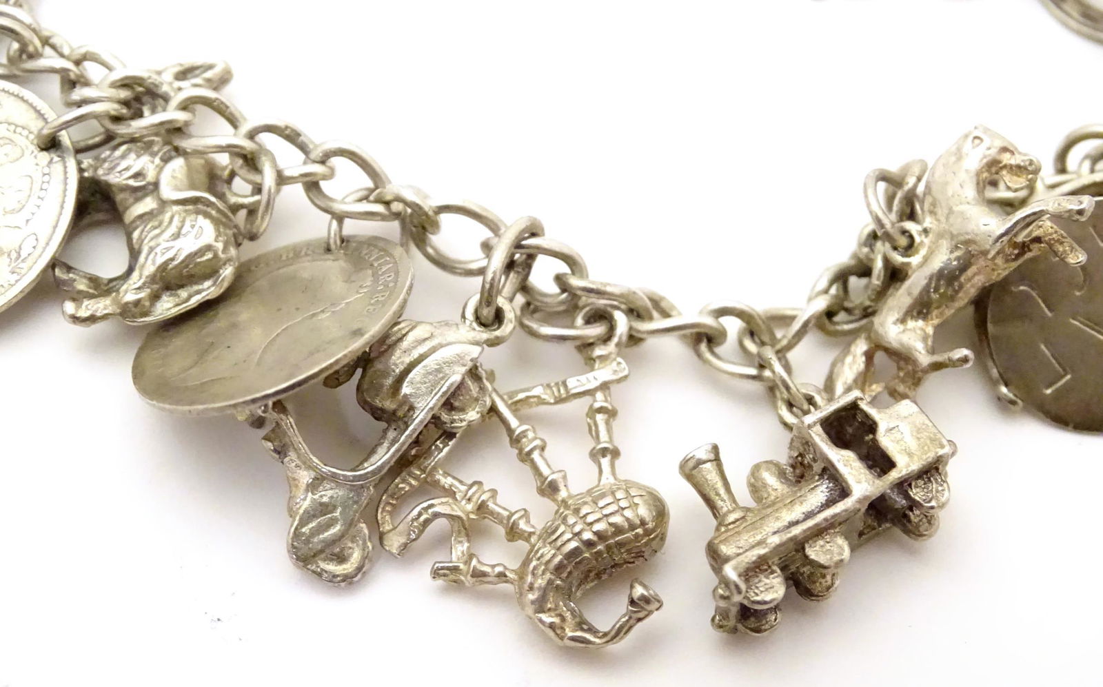 A silver / white metal charm bracelet set with various (1 of 7)