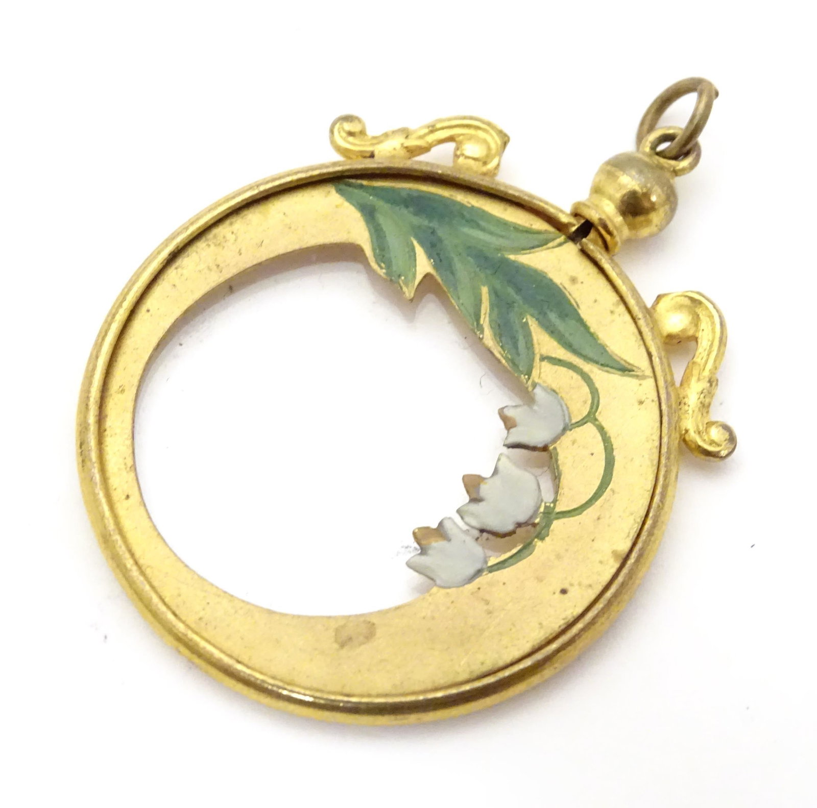 A gilt metal pendant locket with enamel lily of the: A gilt metal pendant locket with enamel lily of the valley detail. Approx 1" high