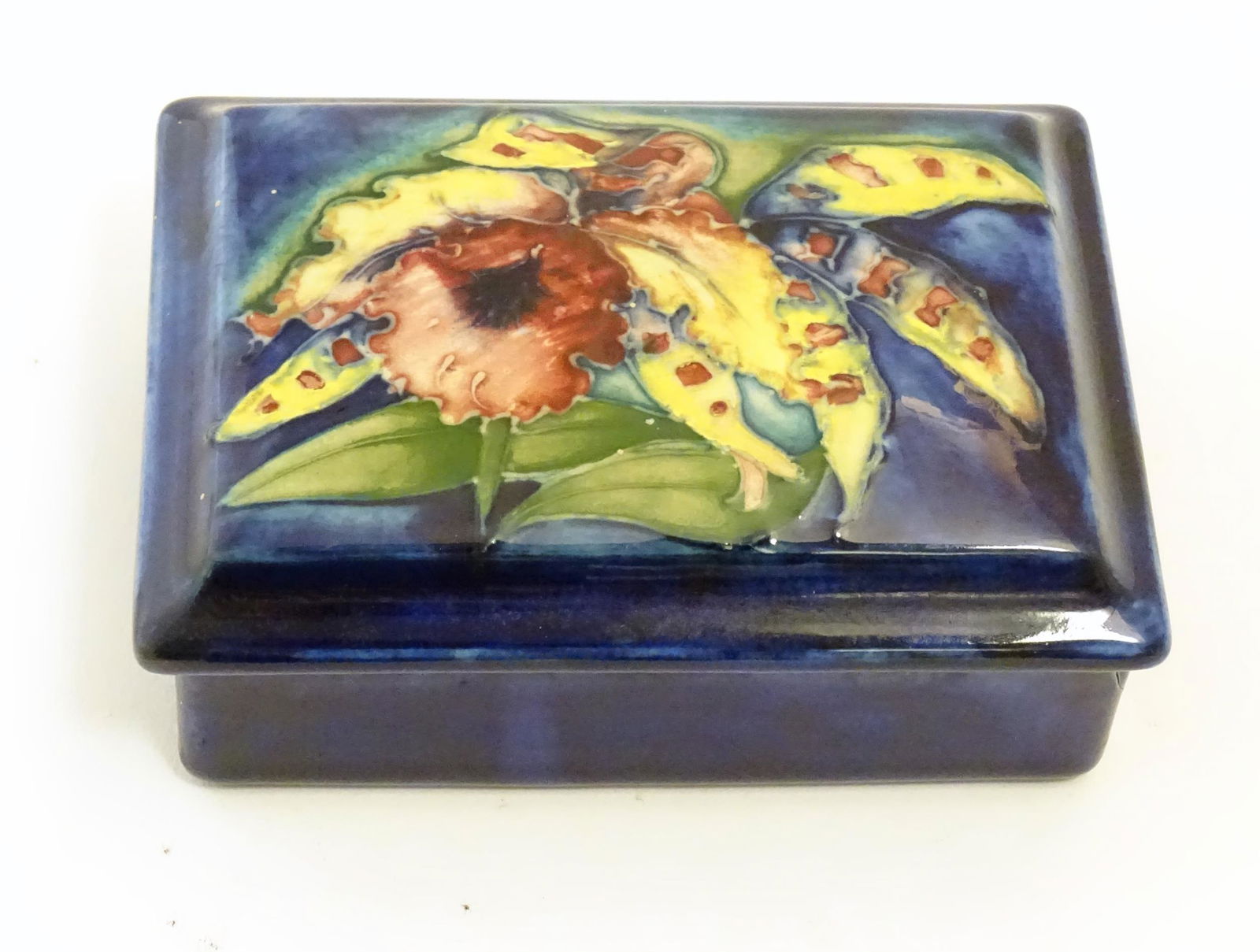 A Moorcroft lidded box of rectangular form in the Orchid pattern. Marked under W. Moorcroft. Approx. (1 of 10)