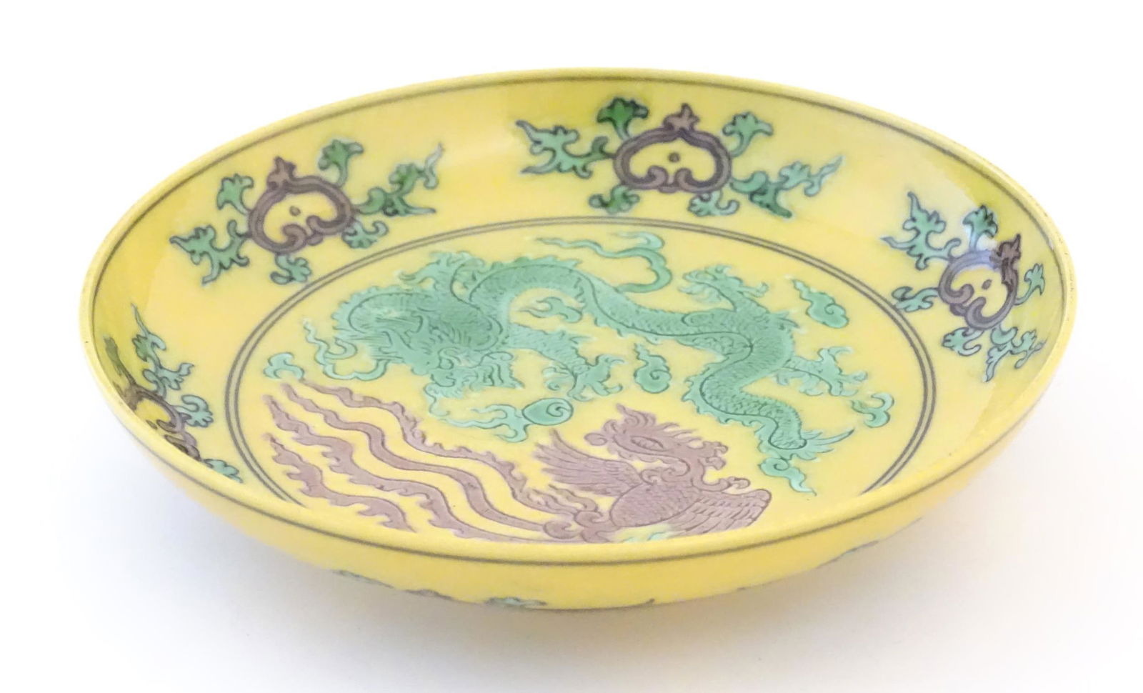 A small Chinese plate with a yellow ground with dragon and phoenix bird decoration. Character marks: A small Chinese plate with a yellow ground with dragon and phoenix bird decoration. Character marks under. Approx. 5 1/4" diameter