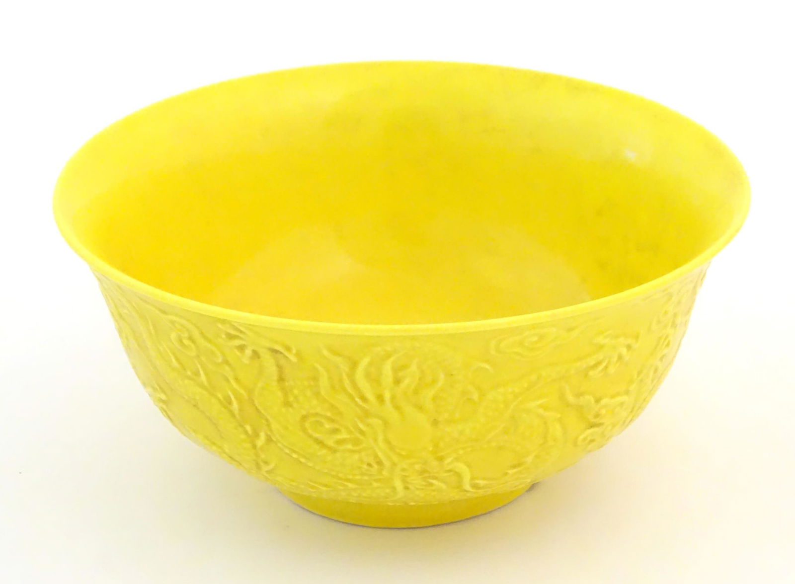 A Chinese bowl with a yellow ground decorated in relief with dragons amongst stylised clouds.: A Chinese bowl with a yellow ground decorated in relief with dragons amongst stylised clouds. Character marks under. Approx. 2 3/4" high x 6" diameter