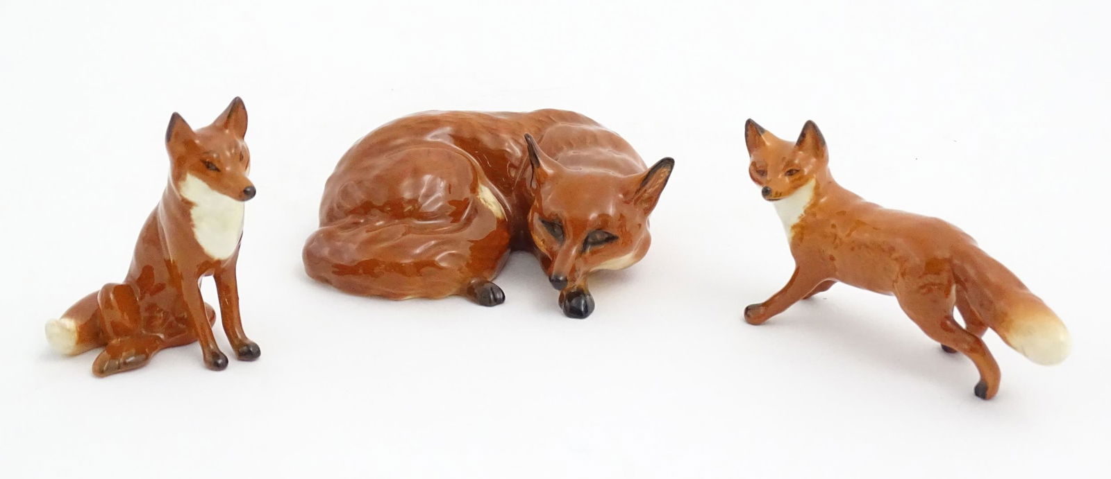 Three Beswick models of foxes, comprising a seated fox, no. 1728, a standing fox, no. 1440, and a (1 of 9)
