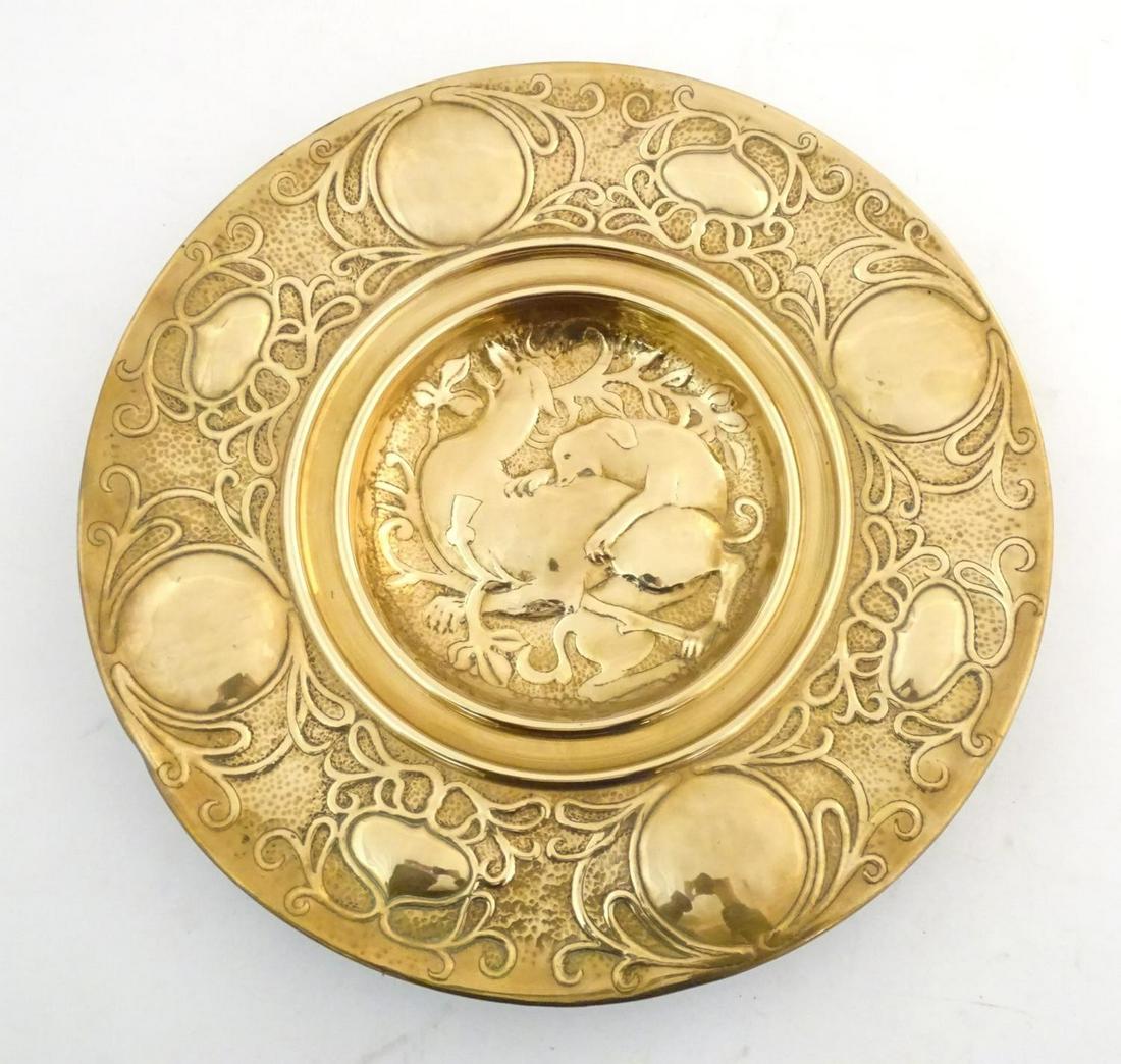An Arts Nouveau brass charger with hammered detail, the central section with embossed stylised (1 of 2)