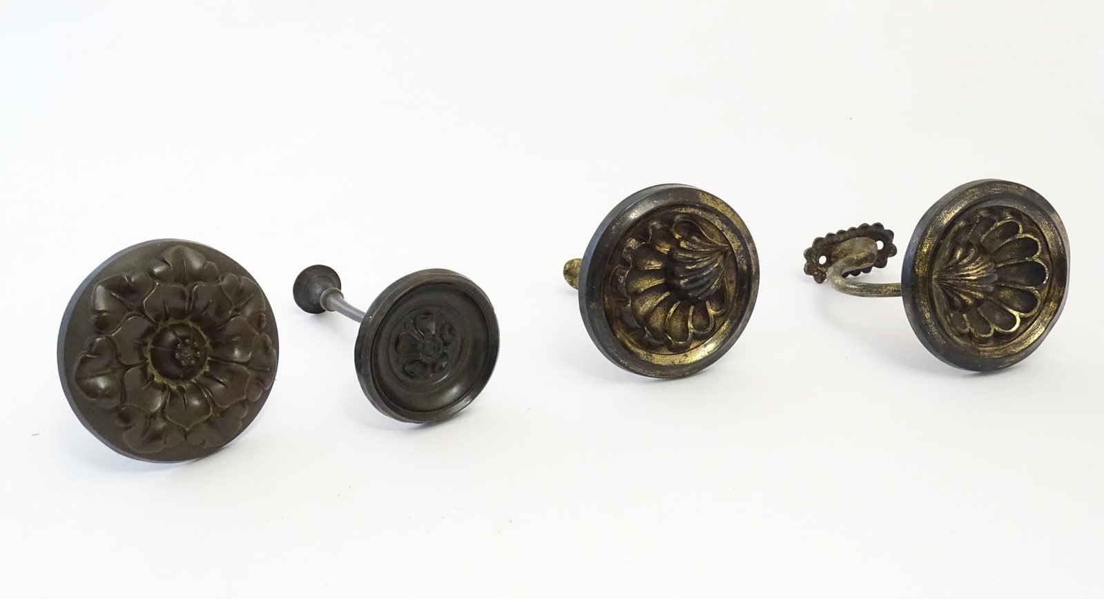 A pair of late 19th / early 20thC gilt metal curtain tiebacks with shell detail. Together with a: A pair of late 19th / early 20thC gilt metal curtain tiebacks with shell detail. Together with a single curtain tie of medallion form with rosette / flower decoration, and a smaller example. Shell tie