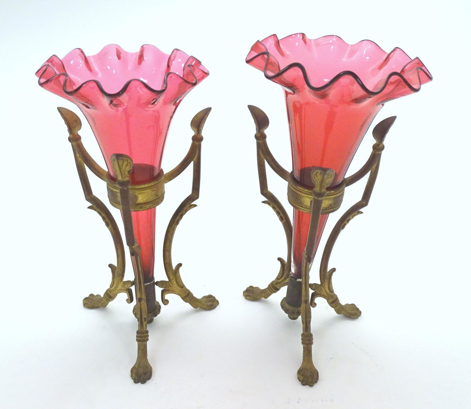 A pair of Victorian epergnes with cranberry glass flutes supported within a gilt brass base with: A pair of Victorian epergnes with cranberry glass flutes supported within a gilt brass base with lions paw feet. 8" high Please Note - we do not make reference to the condition of lots within descript