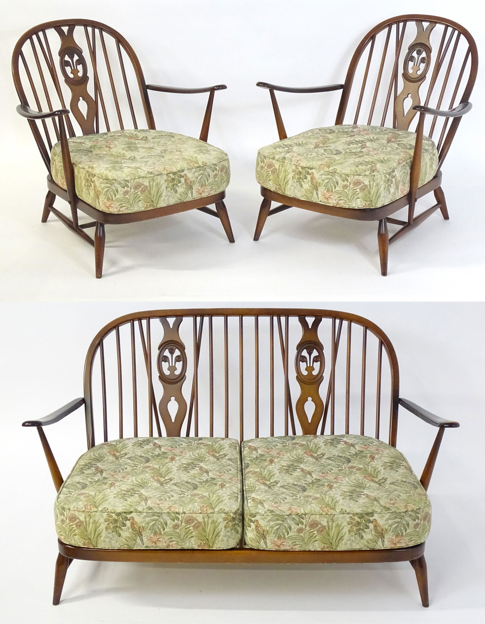 A mid / late 20thC Ercol suite, comprising two armchairs and a settee. Having bowed backs with: A mid / late 20thC Ercol suite, comprising two armchairs and a settee. Having bowed backs with turned spindles and floral upholstered seats and backrests, the chairs raised on turned tapering legs. Th