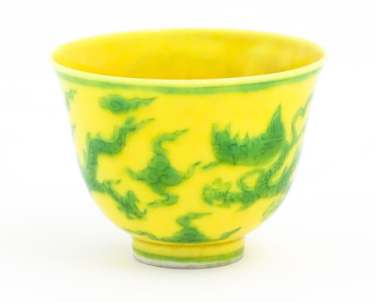 A Chinese wine cup the yellow ground decorated with green dragons and stylised clouds. Character: A Chinese wine cup the yellow ground decorated with green dragons and stylised clouds. Character marks under. Approx. 1 3/4" high