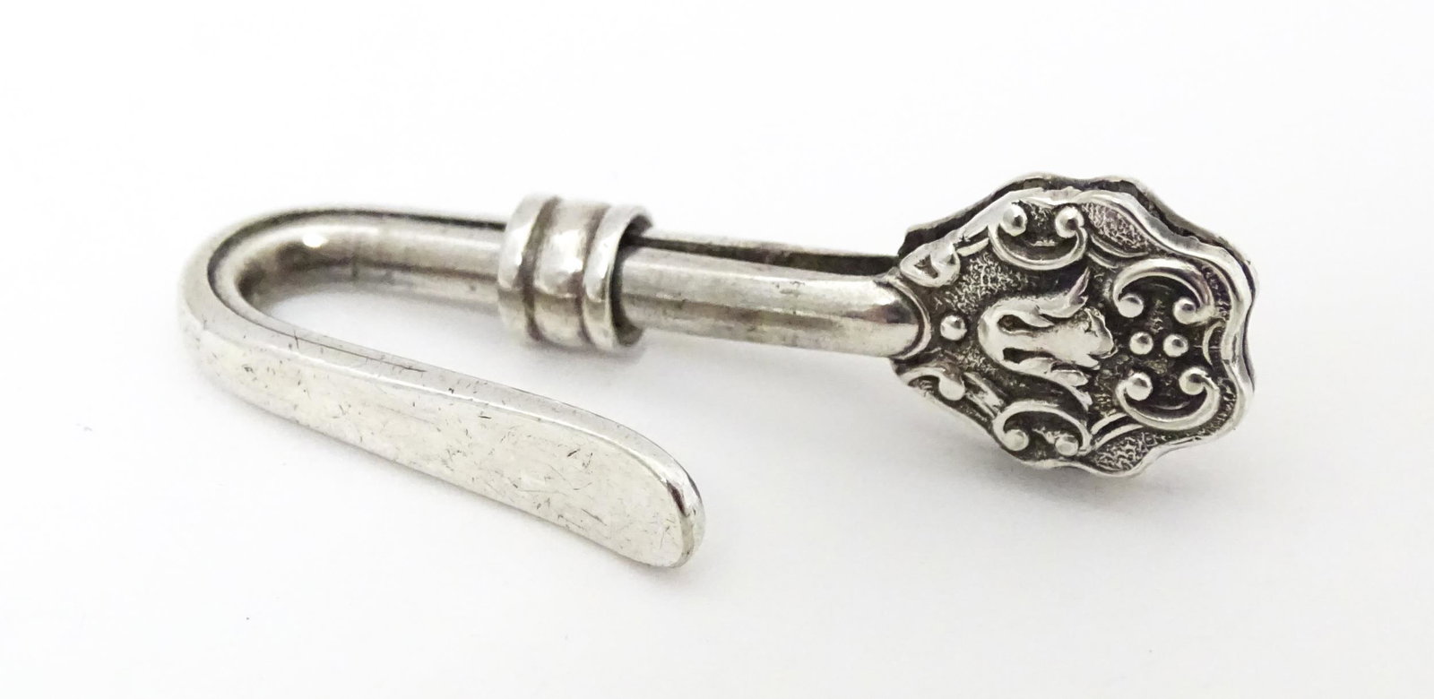 A white metal napkin clip. Approx. 1 1/2" long: A white metal napkin clip. Approx. 1 1/2" long