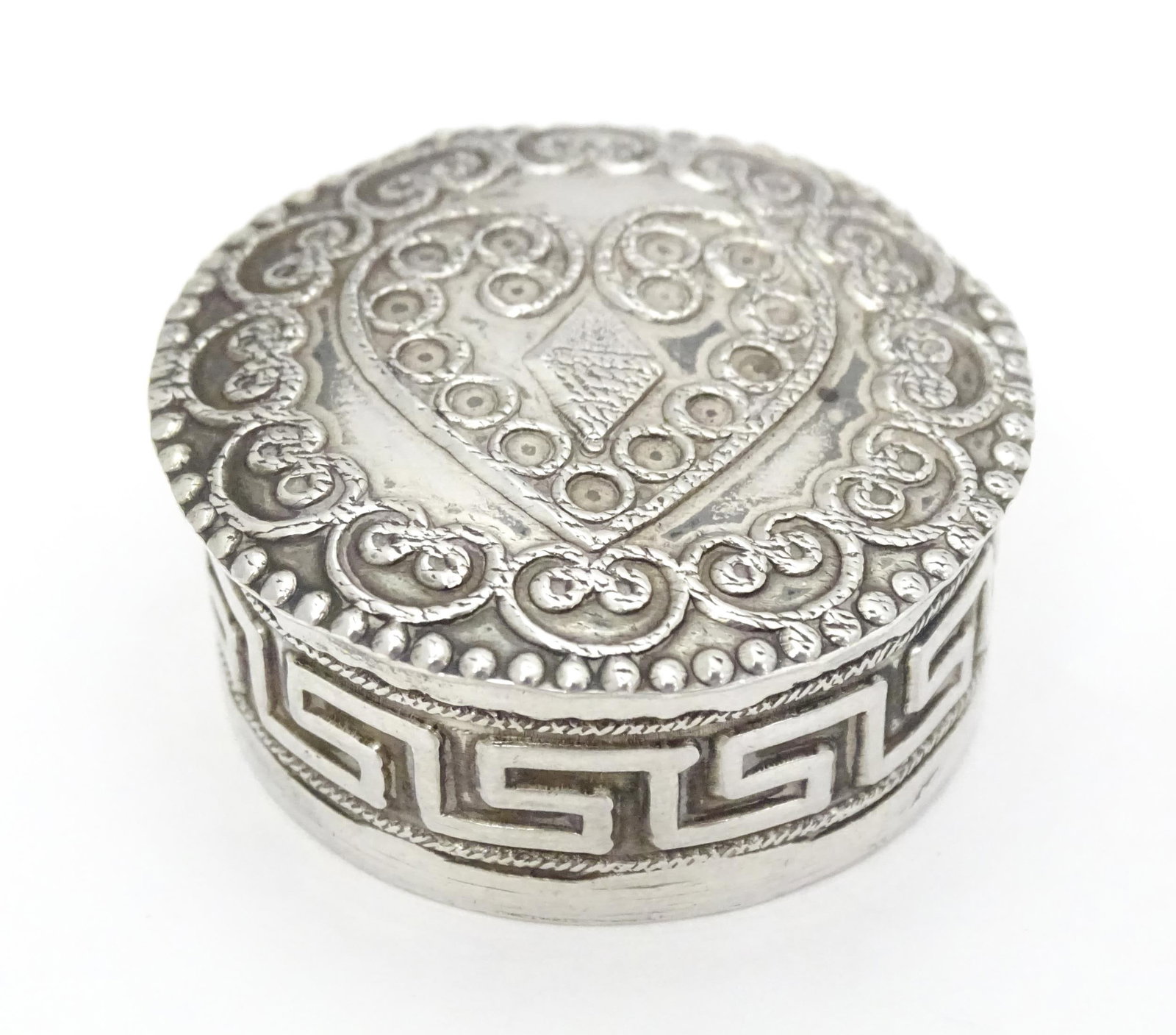 A white metal pill box of circular form heart detail to lid. Approx. 1 1/4" diameter Please Note -: A white metal pill box of circular form heart detail to lid. Approx. 1 1/4" diameterPlease Note - we do not make reference to the condition of lots within descriptions. We are however happy to provide