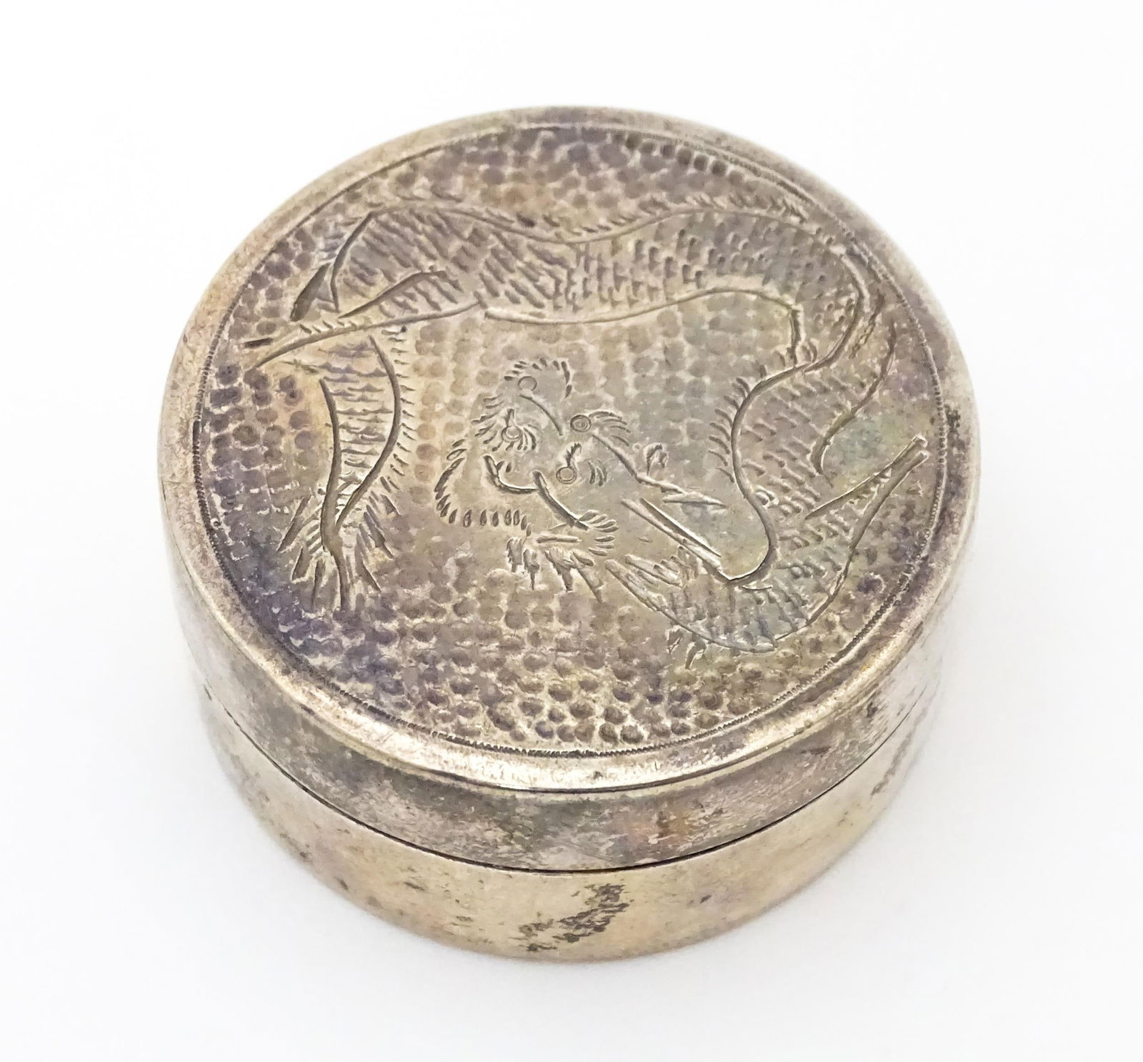 A silver pill box with engraved Oriental dragon decoration to lid, marked sterling, maker W.K.: A silver pill box with engraved Oriental dragon decoration to lid, marked sterling, maker W.K. Approx. 1 1/2" diameterPlease Note - we do not make reference to the condition of lots within description